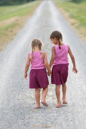 Two young girls holding hands walking down road