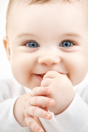 Close up of baby smiling and sucking on thumb