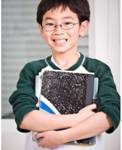 A boy holding a notebook and other school supplies.