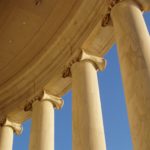 A low-angle view of a grand classical building with tall, white columns and a pedimen