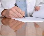 A businessman's hands as he signs a document.
