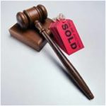 A judge's gavel next to a stack of tags with "SOLD" written on them.