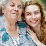 A smiling grandmother and granddaughter pose for a portrait.