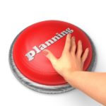 A human hand presses a large, round red button and the word "Planning" is embossed on its surface.
