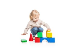 Baby girl building from toy blocks. isolated on white background.
