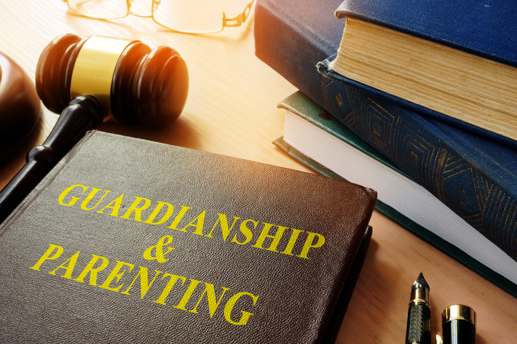 A book with the title "Guardianship & Parenting". on desk next to gavel and books