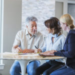 Elderly father at home with adult daughter discussing estate plan