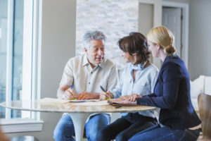 Elderly father at home with adult daughter discussing estate plan